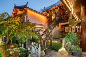 A traditional building with a staircase leading to a balcony, surrounded by potted plants and a small garden.