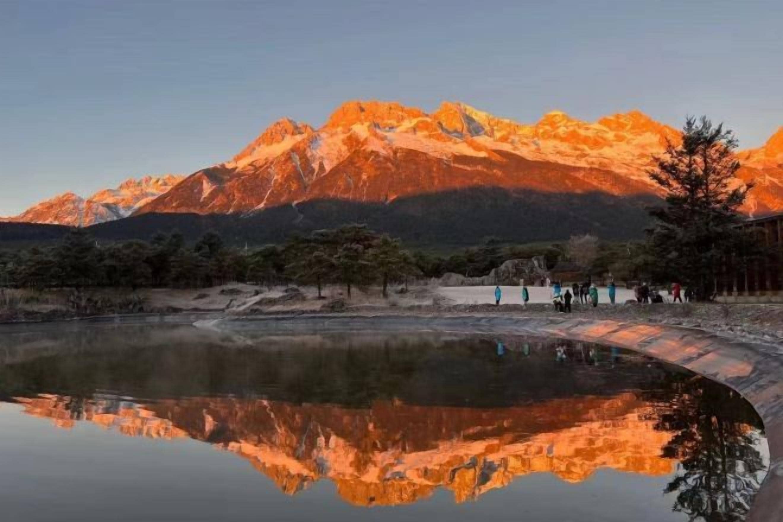 Una cordillera reflejada en aguas tranquilas bajo un cielo despejado.