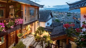 A traditional building with a balcony, potted plants, and a view of the cityscape.
