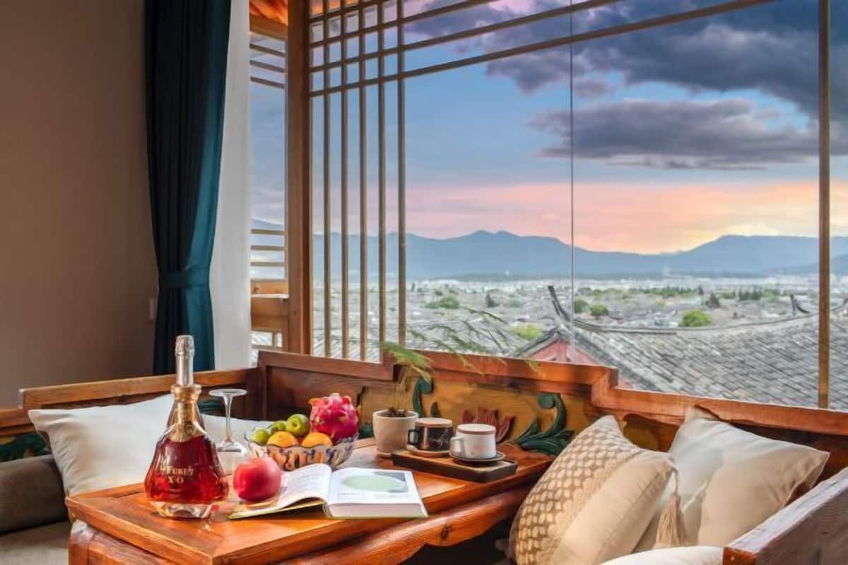 A room with a wooden bench, a bottle, fruits, a cup, and a book.