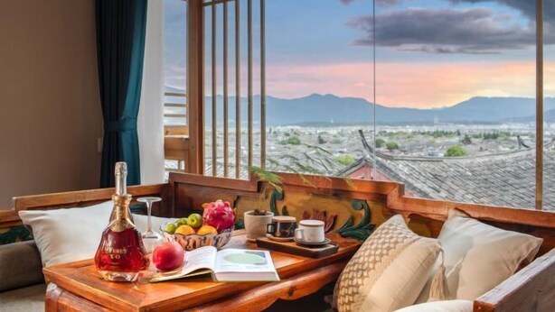 A room with a wooden bench, a bottle, fruits, a cup, and a book.