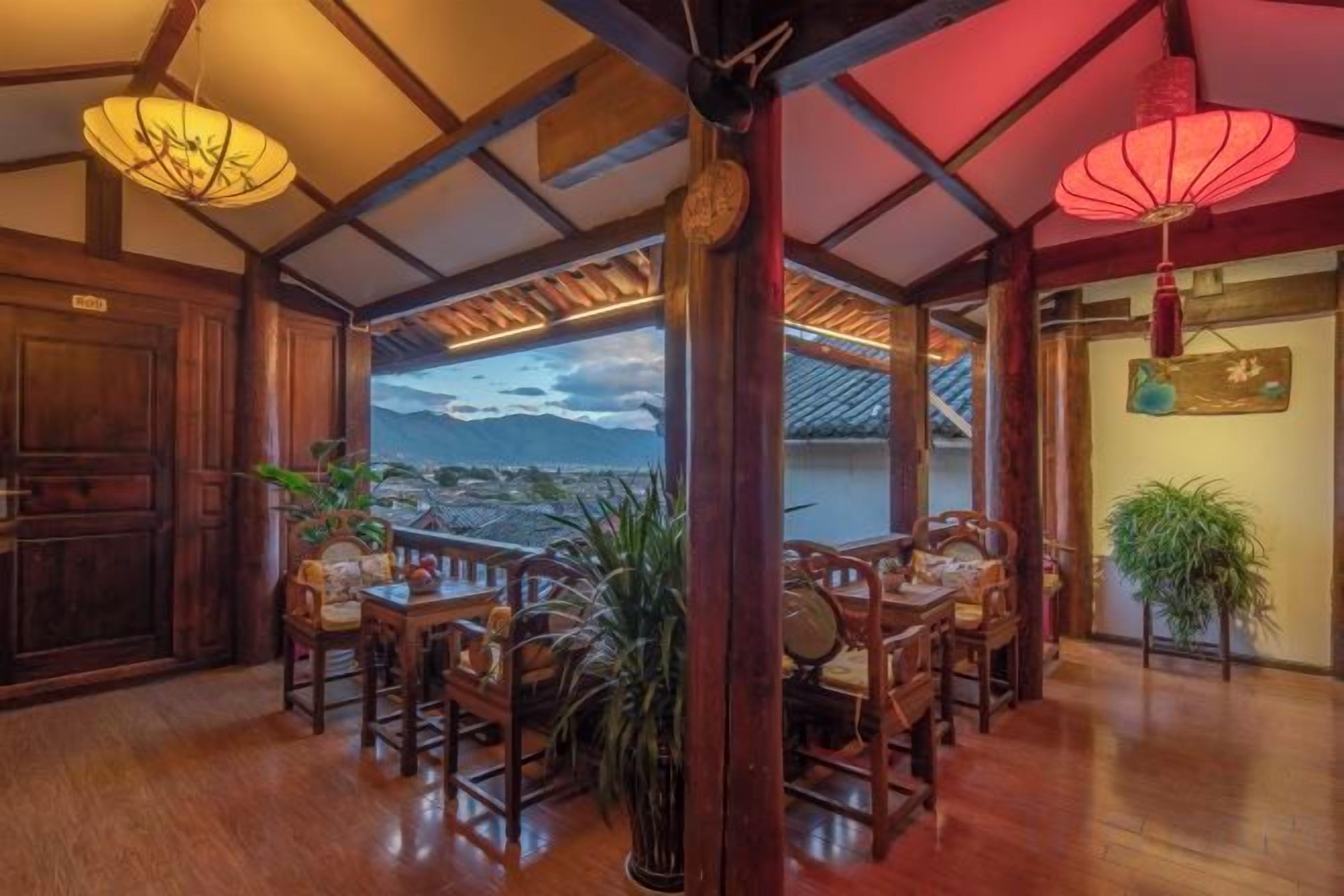 A traditional wooden interior with a dining area, a view of the mountains, and a red lantern.