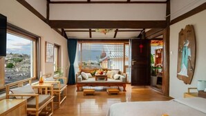 A room with a bed, wooden furniture, a view through large windows, and traditional decor.