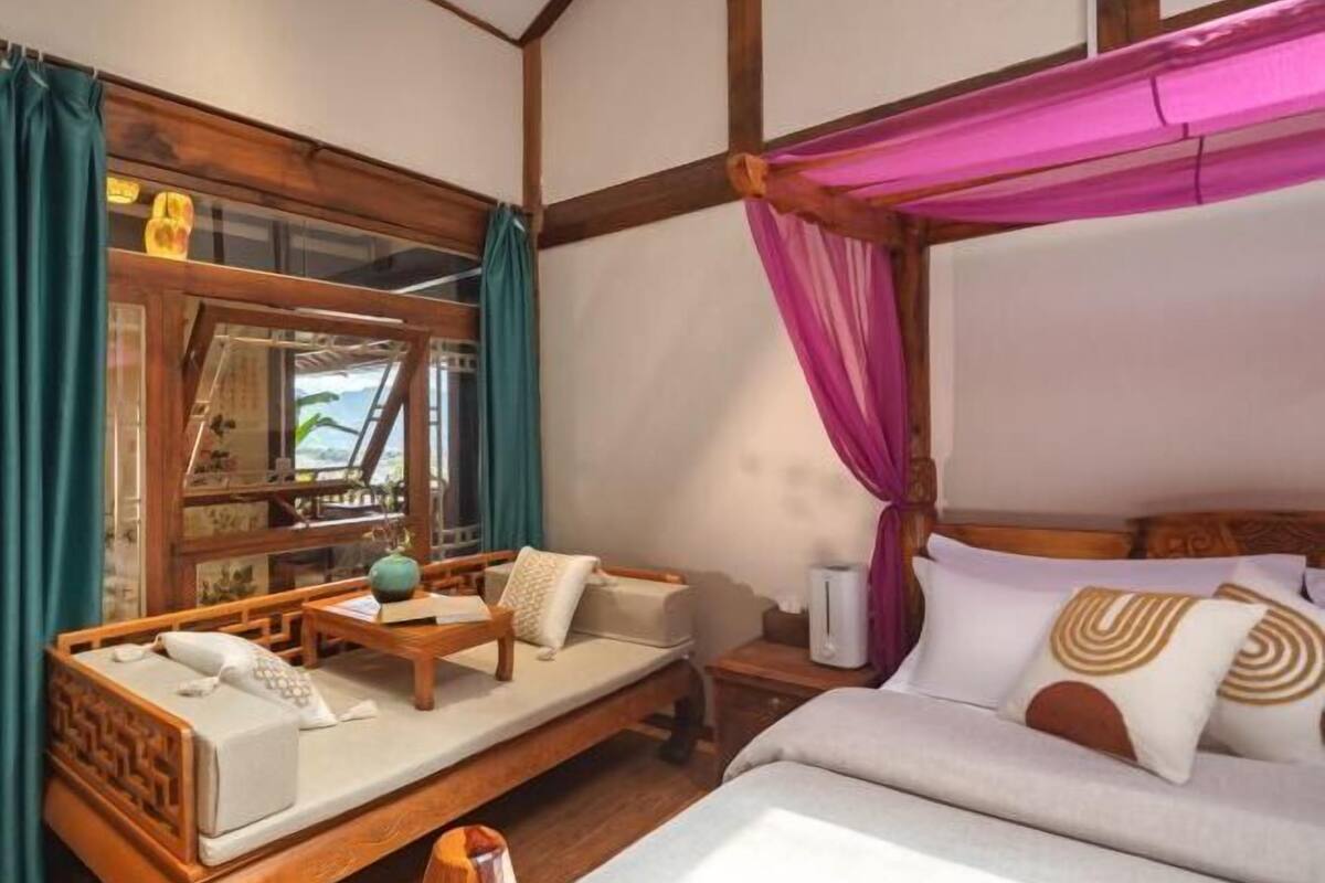 A traditional-style room with a bed, a wooden bench, and a small table.