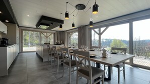 A modern kitchen with a dining area, large windows, and a view of the outdoors. - Lu T'Chêne - dans le Village d'Opont (Opont)