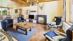 Una sala de estar acogedora con chimenea, asientos cómodos, televisor y candelabro.