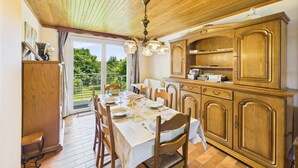 Comedor con una mesa dispuesta para cuatro personas, armarios de madera y vista a zonas verdes.