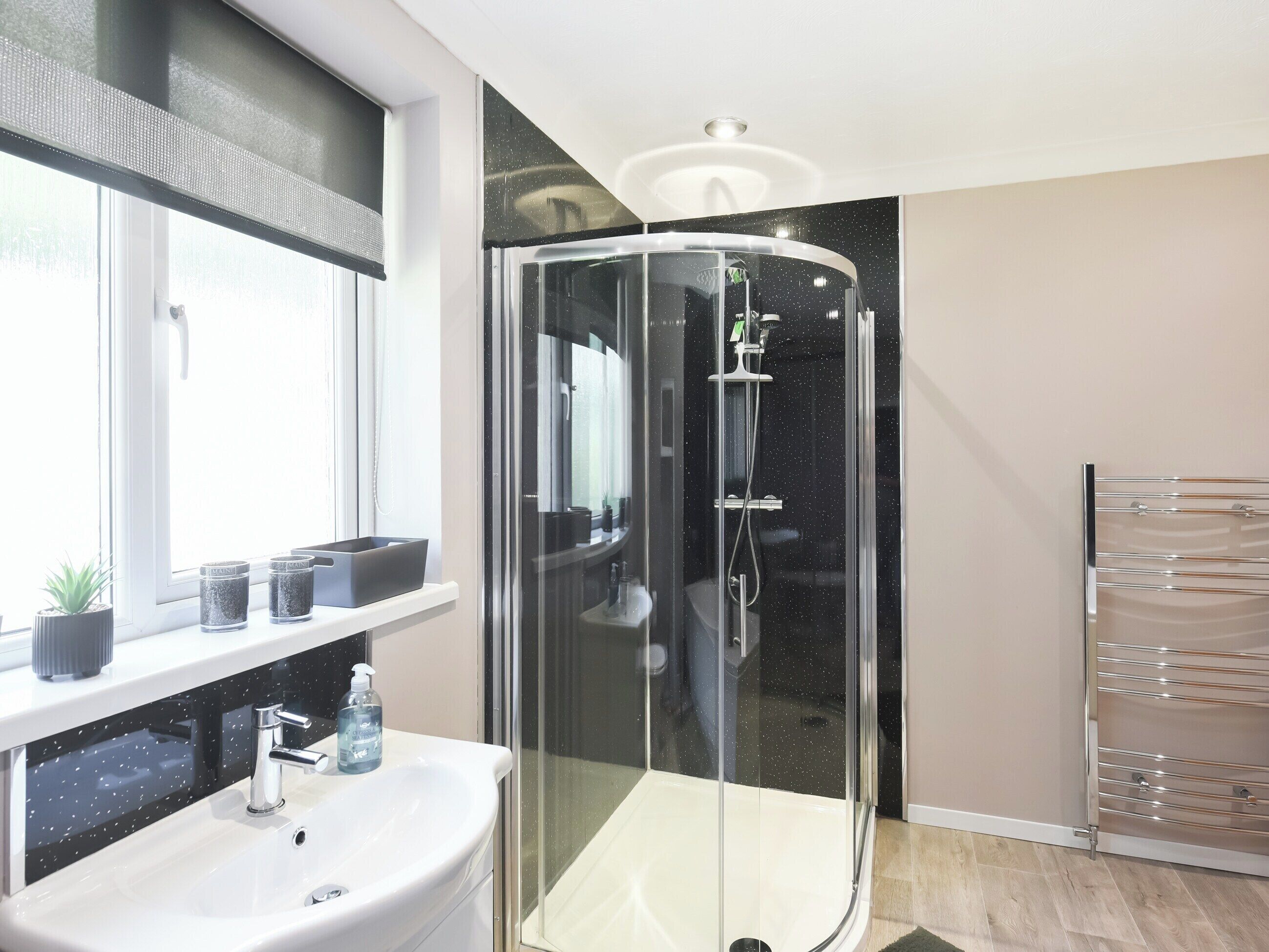 A modern bathroom with a glass-enclosed shower, a white sink, and a mirror above it.