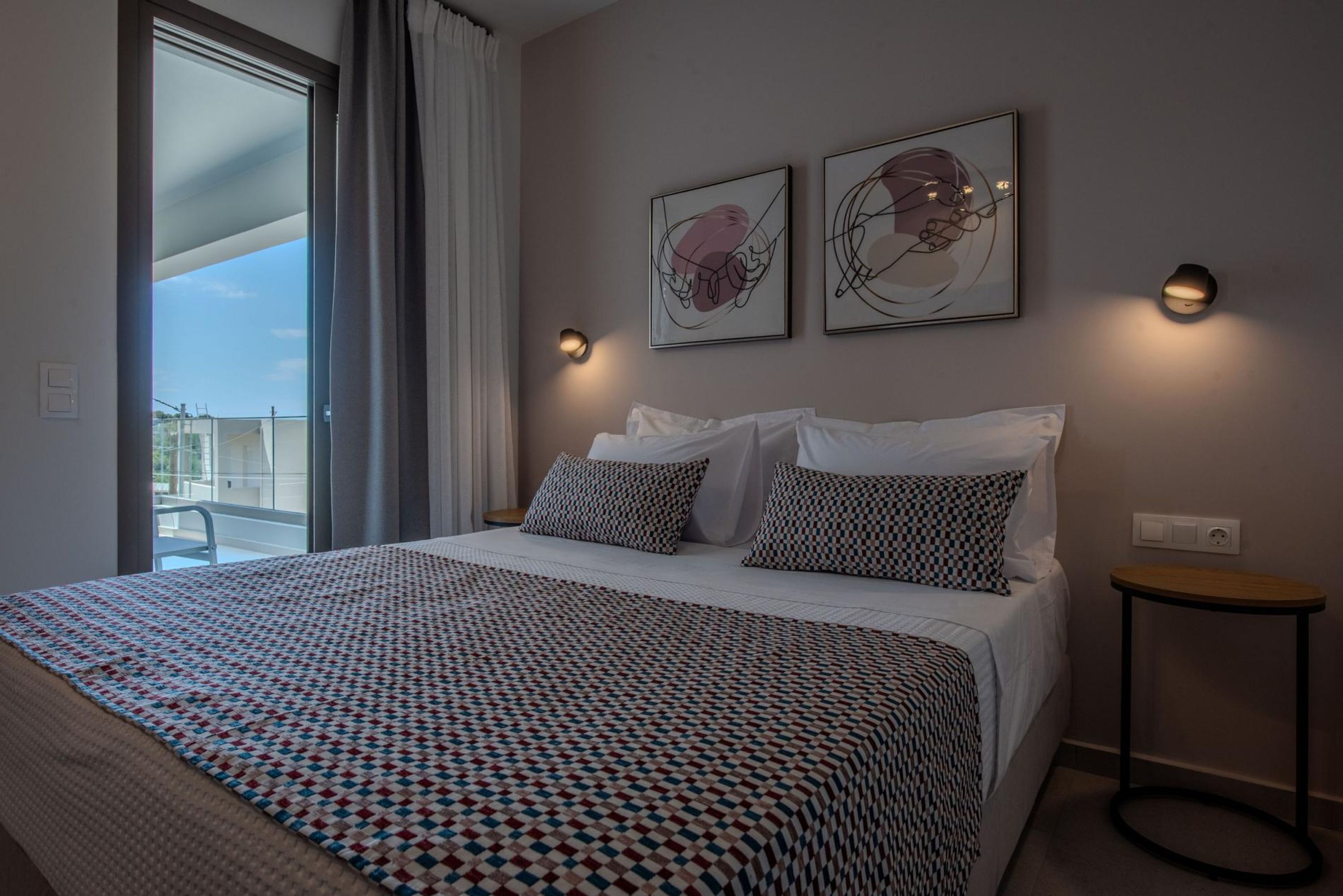 Ein Hotelzimmer mit einem großen Bett, zwei Wandleuchten und zwei gerahmten Kunstwerken darüber.