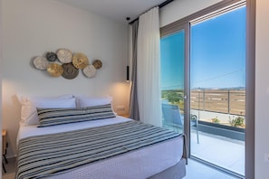 Une chambre à coucher comprenant un lit, une table de chevet, une assiette décorative accrochée au mur et un balcon avec vue.