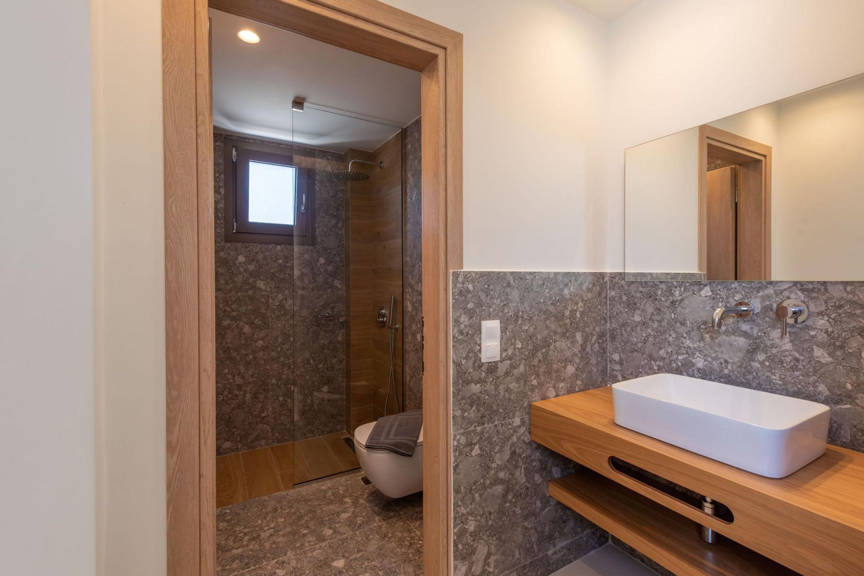 Une salle de bain moderne avec un lavabo rectangulaire, un meuble-lavabo en bois et une douche à parois de verre.
