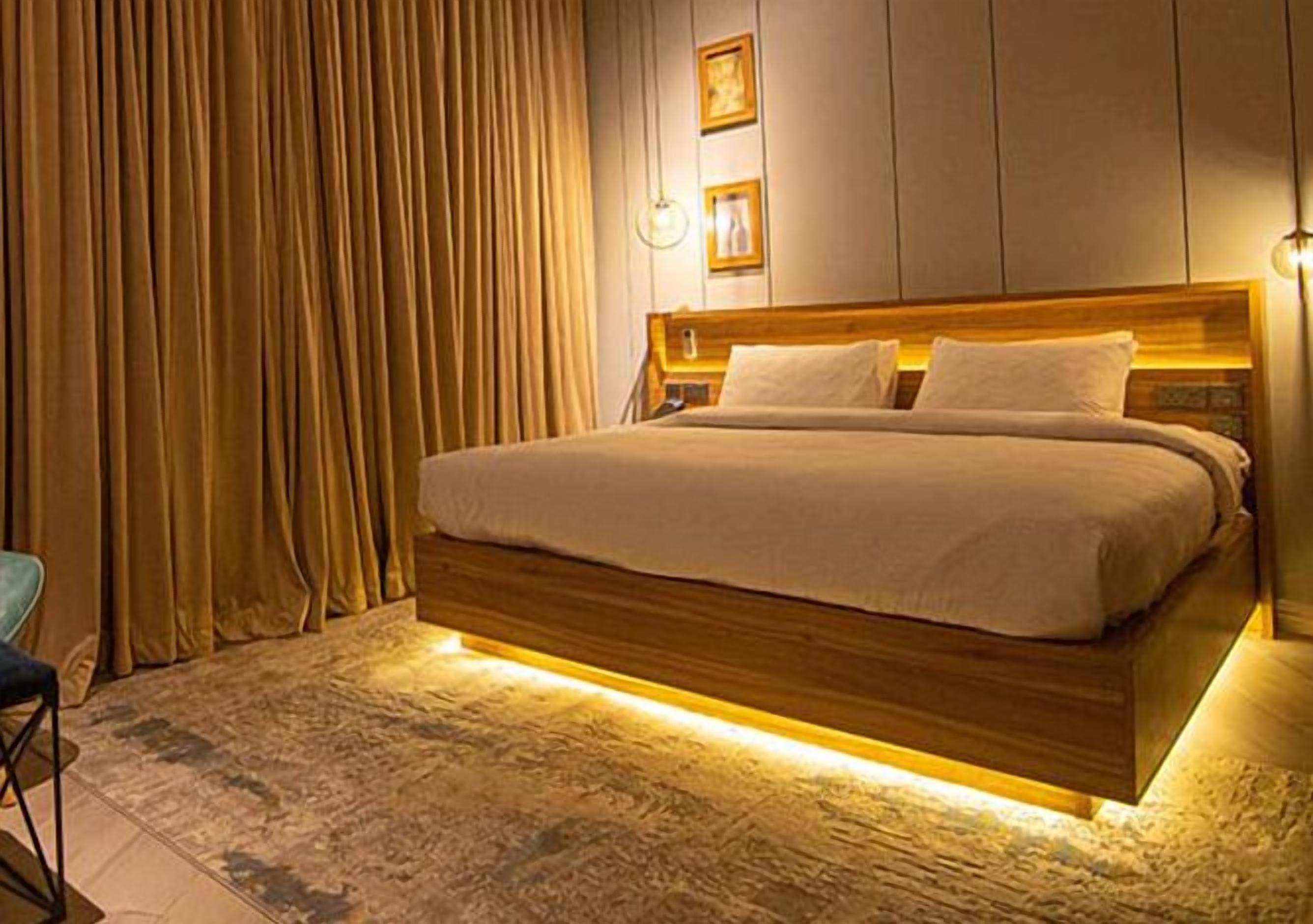 A hotel room with a large bed, wooden headboard, and a carpeted floor.