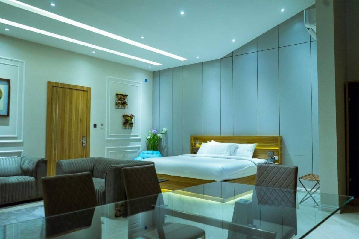 Une chambre d’hôtel moderne avec un grand lit, une table basse en verre, un canapé et une petite table d’appoint.