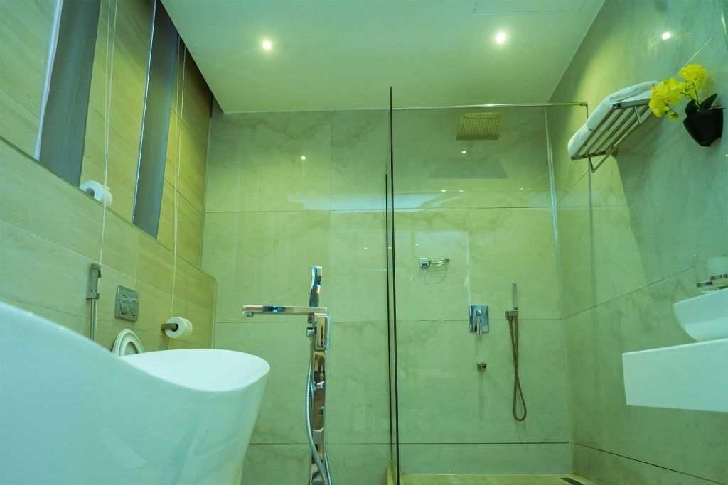 A modern bathroom with a glass-enclosed shower, a white sink, and a towel rack with flowers.