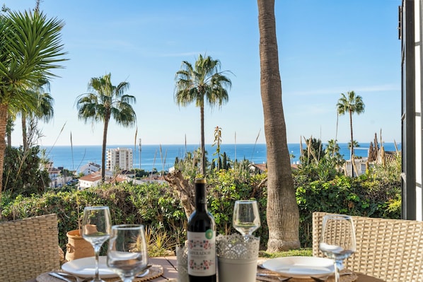 Enjoy a romantic oceanfront dining experience with a view of palm trees and the surrounding landscape.