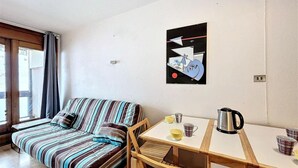 Une petite pièce agréable et chaleureuse, avec un canapé à rayures, une table en bois et une bouilloire.