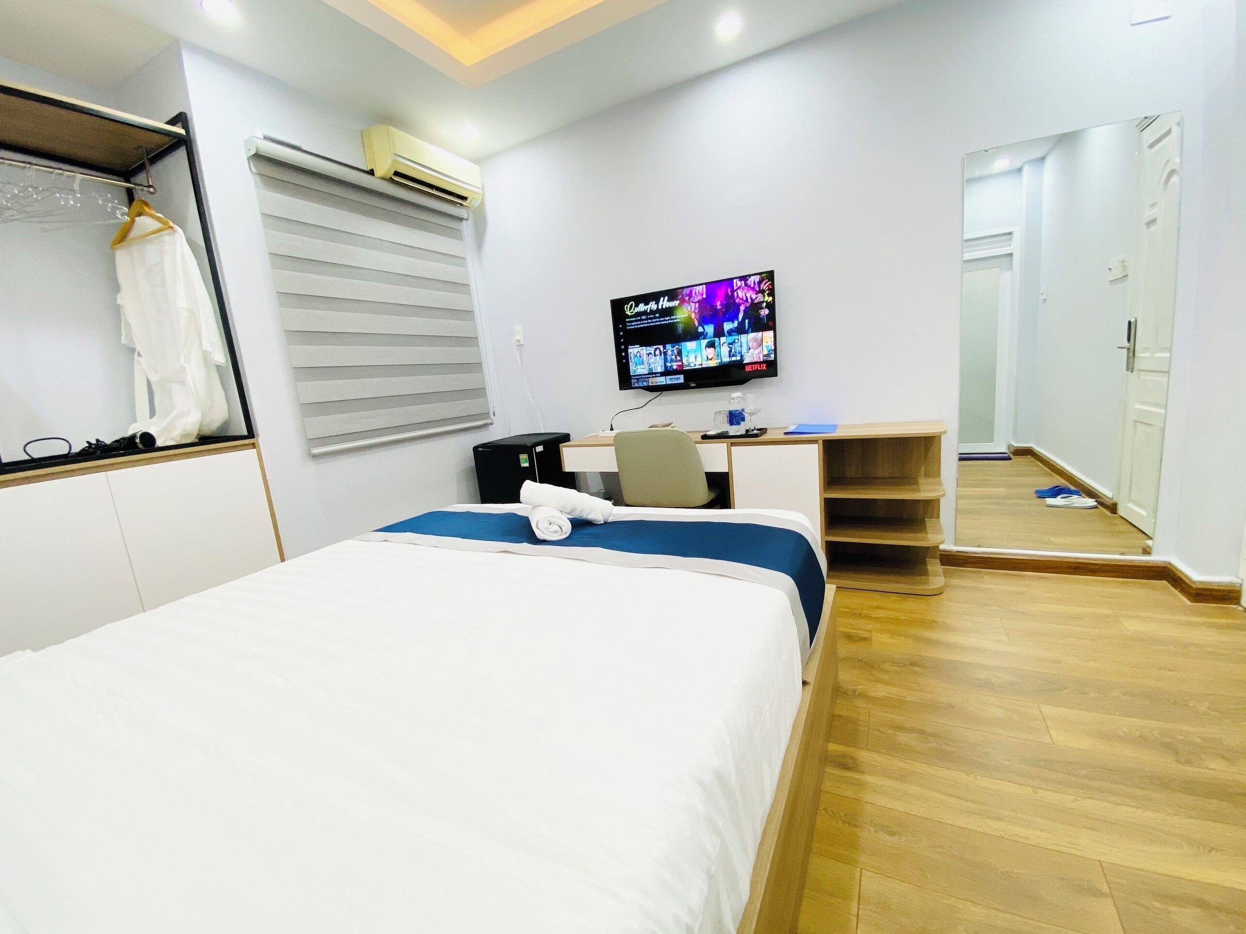Ein Hotelzimmer mit Bett, Schreibtisch, Fernseher und Spiegel.