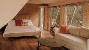 Een ruime tent met een bed, een slaapbank en een ronde salontafel.