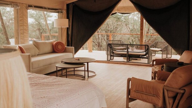 Een gezellige slaapkamer met een bed, een bank, een eettafel en stoelen. Er is een groot raam en uitzicht op de omgeving.