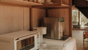Een keuken met houten kastjes, een witte toaster, een koffiezetapparaat en een roestvrijstalen koelkast.