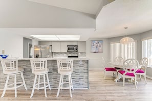 A modern kitchen with a central island, bar stools, and a dining table with chairs. - 9 Mi to Beach! Poolside Escape in Spring Hill (Spring Hill)