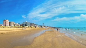 Une plage avec une jetée, un rivage sablonneux et des bâtiments en arrière-plan.