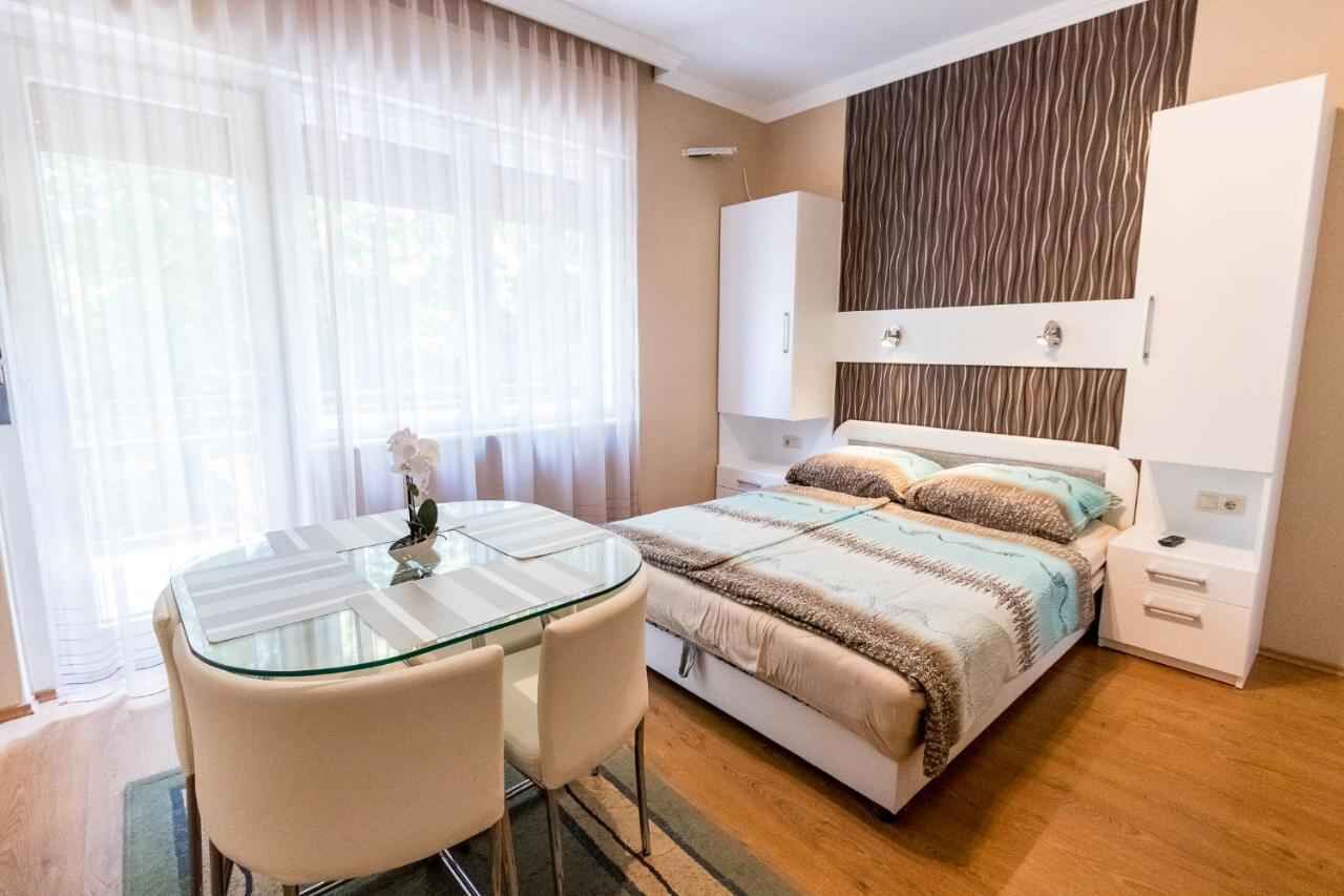 Ein modernes Schlafzimmer mit einem Glastisch, einem Bett mit gestreifter Bettwäsche und einem Kleiderschrank.
