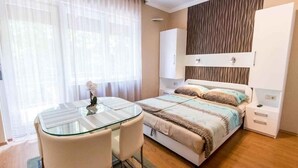 Un dormitorio moderno con una mesa de comedor de cristal, una cama con ropa de cama a rayas y un armario.