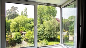 A room with a large sliding glass door leading to a lush garden. - Great location 2 bedroom apartment (London)