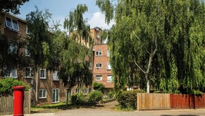 A residential area with brick apartment buildings, a red post box, and a wooden fence. - Great location 2 bedroom apartment (London)