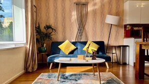 A modern living room with a blue sofa, a round coffee table, and a colorful rug. - Great location 2 bedroom apartment (London)