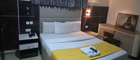 A hotel room with a bed, bedside table, nightstand, dresser, and a painting on the wall.