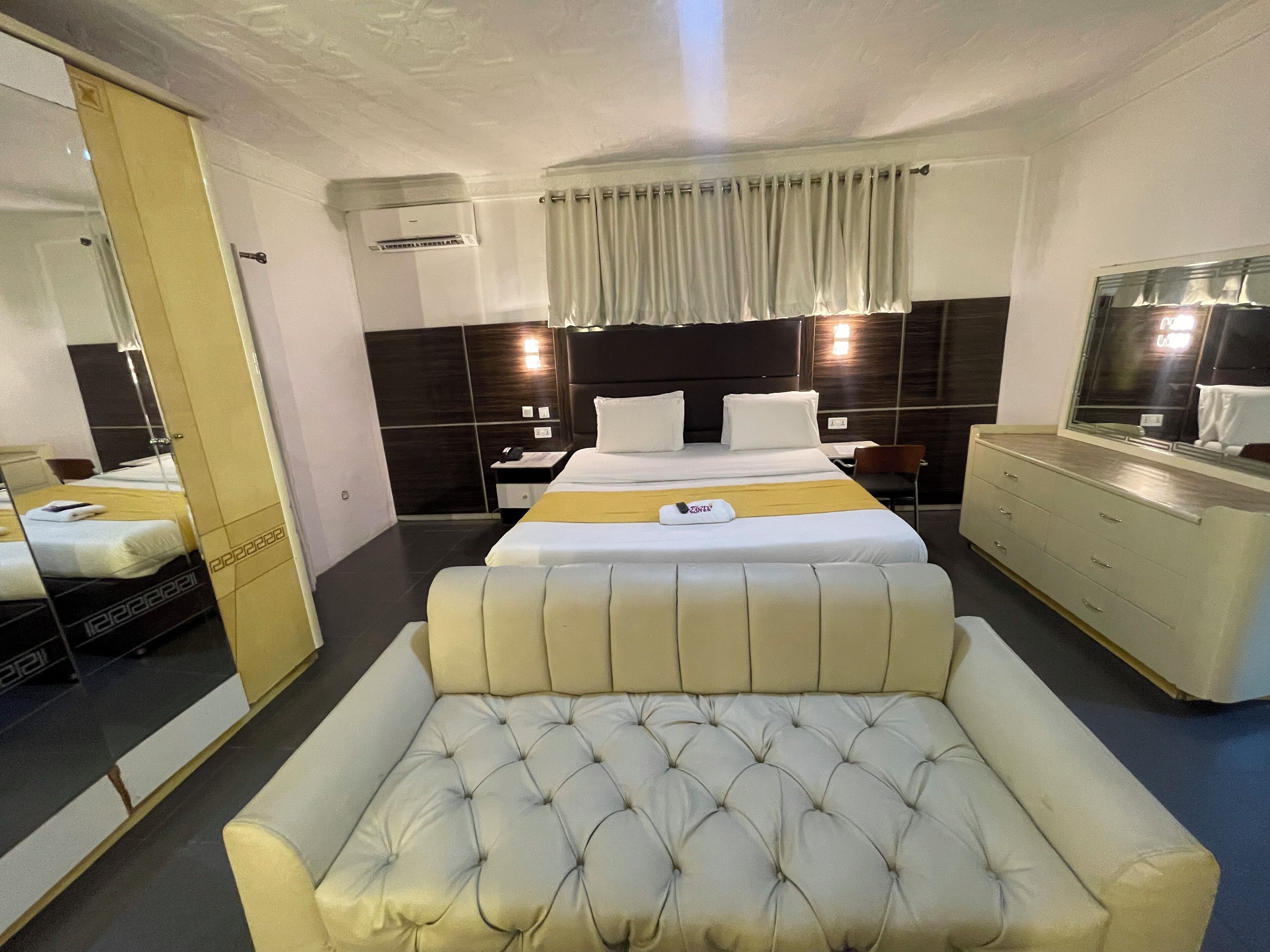 Ett hotellrum med en stor säng, en sittgrupp, en byrå och en spegel.