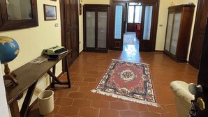 Un pasillo amplio con techo de madera, un globo terráqueo, un escritorio con máquina de escribir y una alfombra estampada.