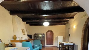 Una cocina con lavadora, una mesa de comedor con sillas, un sillón azul y una puerta de madera.