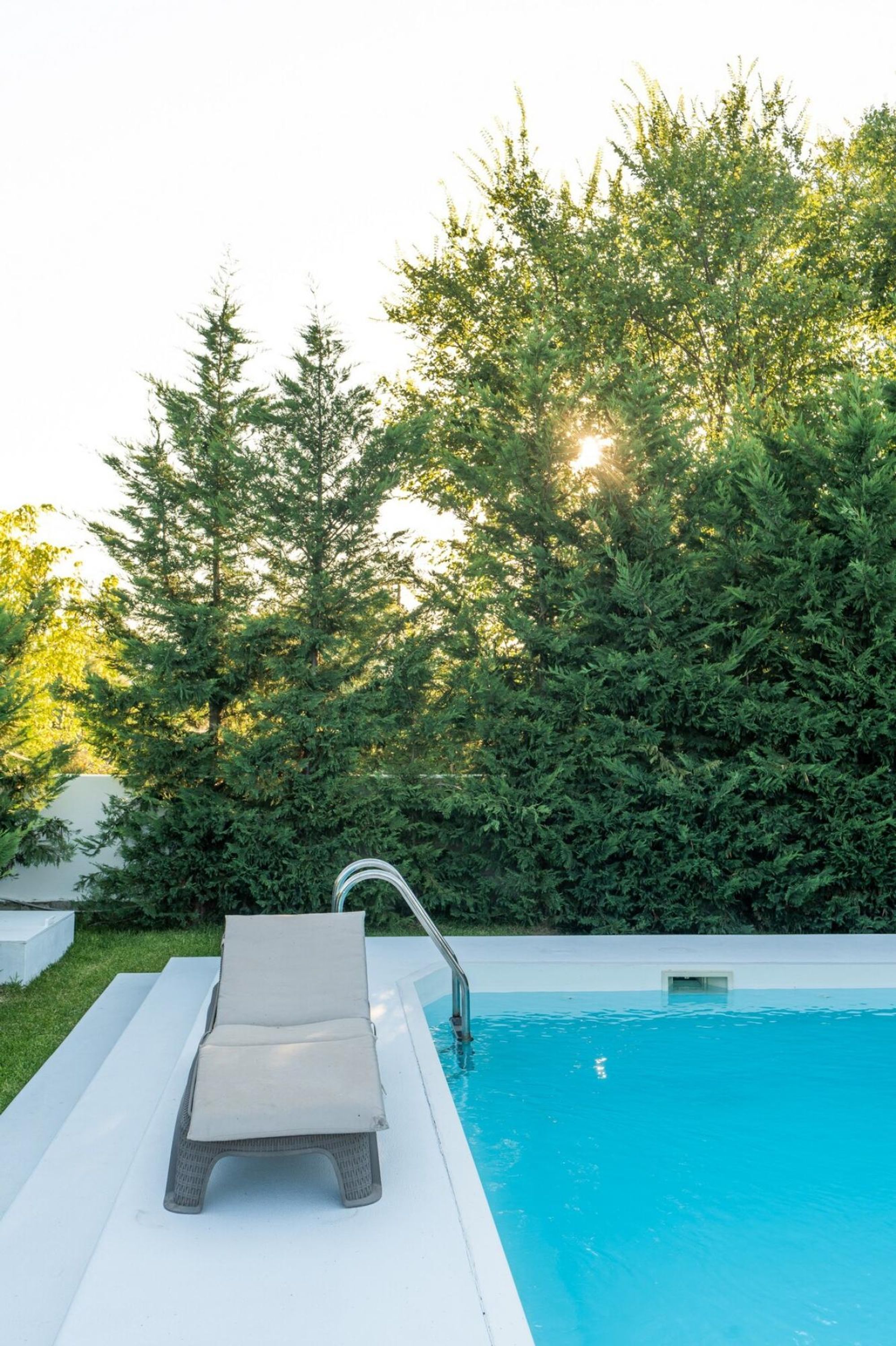 A swimming pool with a lounge chair and a metal ladder.