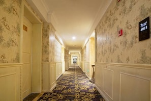 Corredor de hotel com papel de parede estampado, carpete com design floral e placa indicando a suíte número 4001.