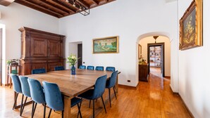 A dining area with a wooden table and blue chairs, a wooden cabinet, and a painting on the wall. - Apartment with view on Piazza Navona (Rome)