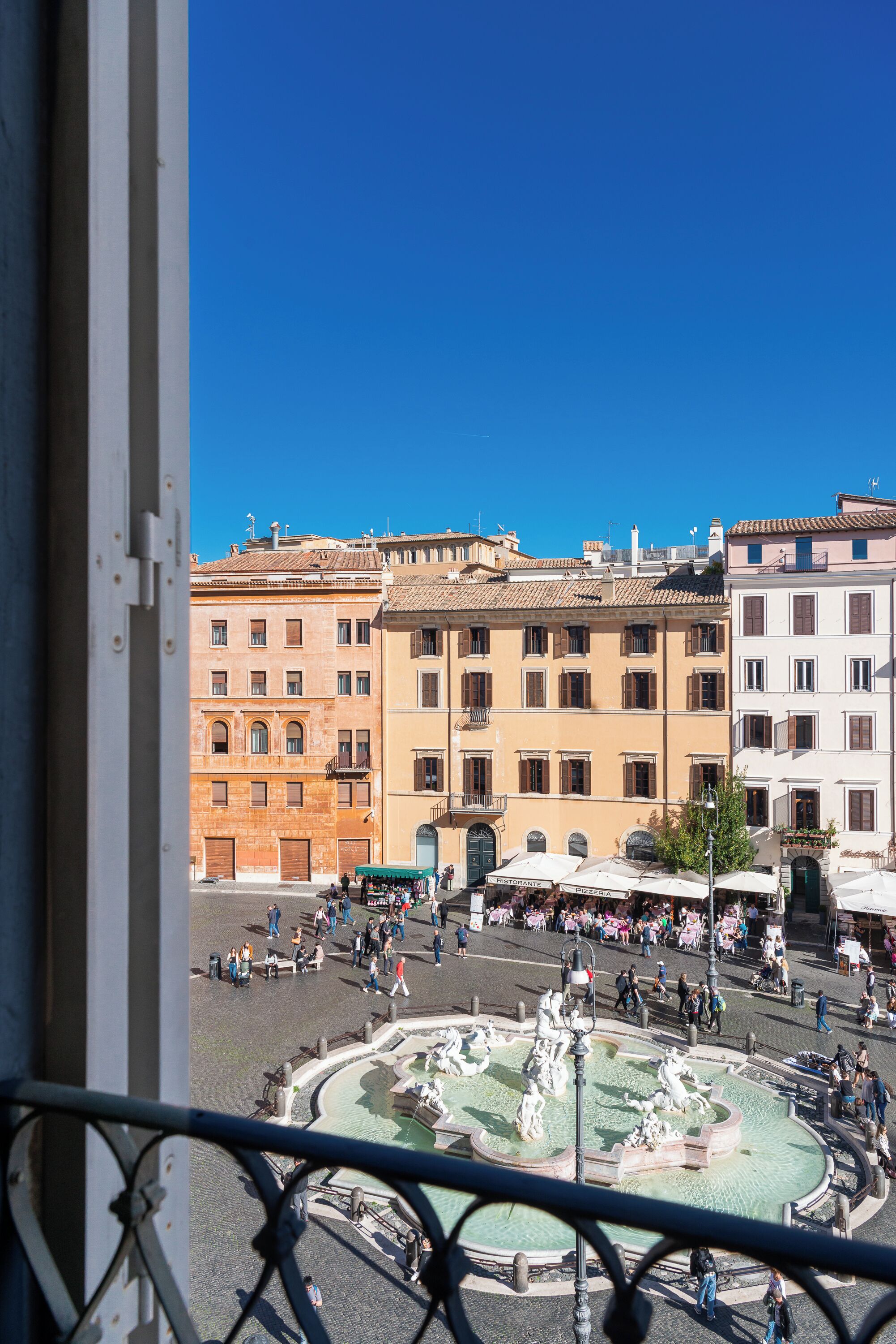 A courtyard with a fountain, surrounded by historic buildings with multiple stories and balconies.