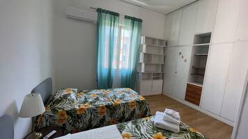 Une chambre avec deux lits, une armoire et une fenêtre avec des rideaux.