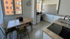 A compact kitchen with a dining area, a sink, and a clock on the wall.