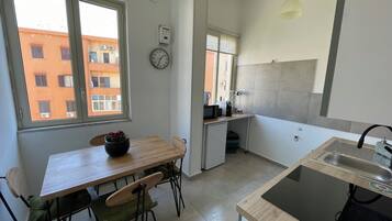 Une cuisine de taille réduite comprenant un coin repas, un évier et une horloge murale.