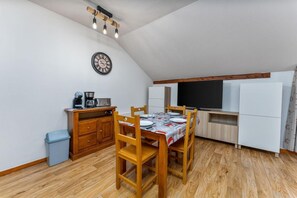 A compact kitchen with a dining area, wooden cabinets, a coffee maker, and a flat-screen TV. - 40m from ski slopes, 4th floor, fitness, swimming pool, sauna, balcony, tv, ski locker, 31m² (Les Orres)