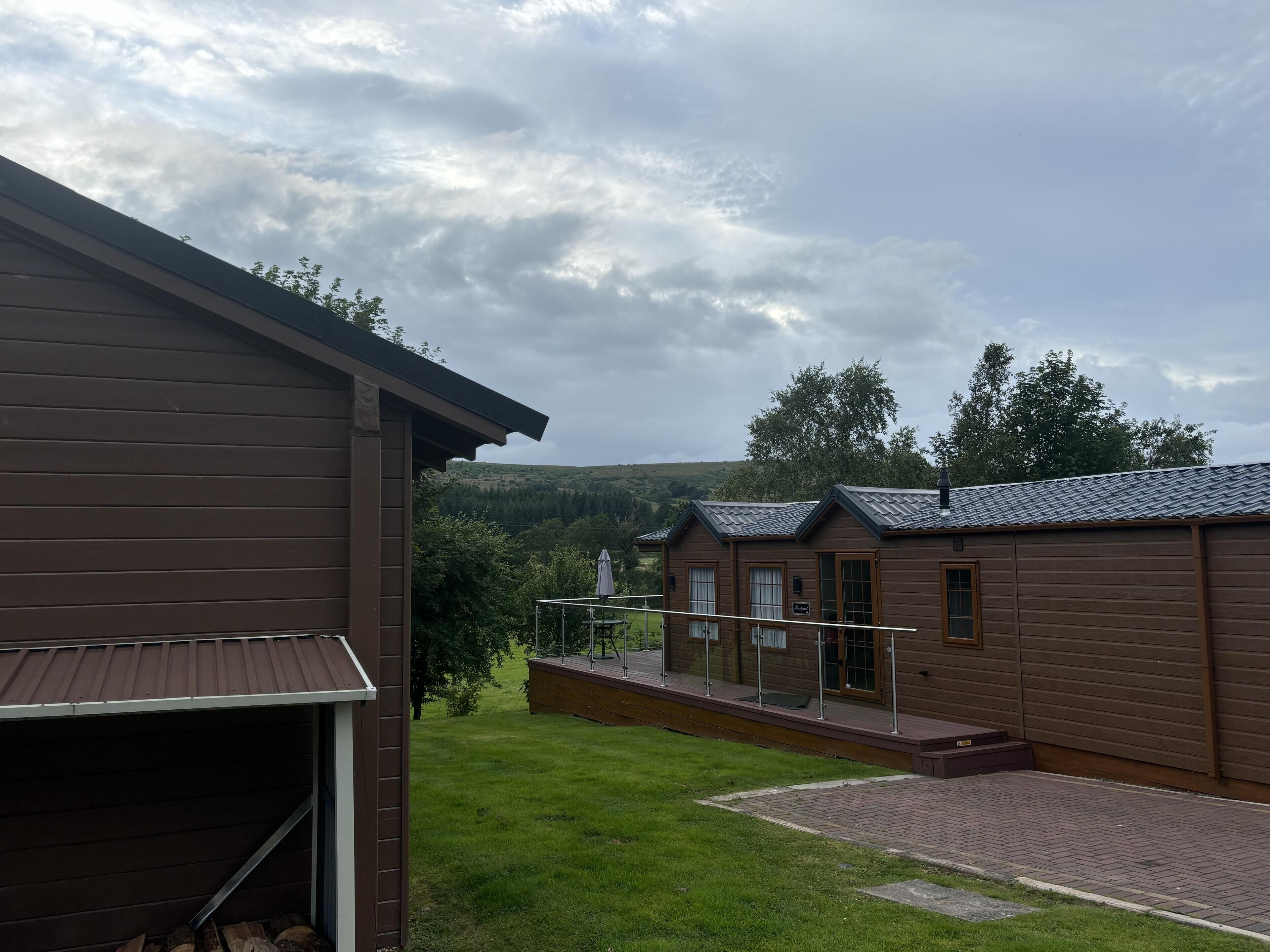 Une cabane en bois dotée d’un porche couvert et offrant une vue sur un paysage vallonné.
