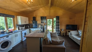 A wooden cabin interior with a kitchen, dining area, and living room. - Pet Friendly - Lodge at Riverview Holiday Park (Newcastleton)