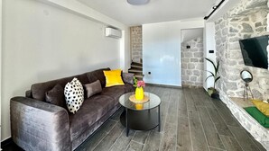 A modern living room with a sofa, a coffee table, and a stone wall. - Villa Vojnic (Kuljace)