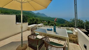 A terrace with a table, chairs, and a large umbrella. - Villa Vojnic (Kuljace)