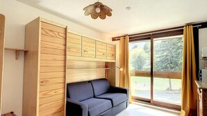 Un soggiorno moderno con un divano, mobili in legno e un'ampia finestra con tende.