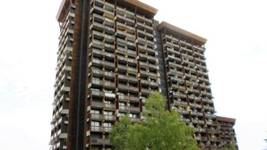 Un hotel di grandi dimensioni con numerosi balconi, un cartello di un ristorante e vegetazione rigogliosa in primo piano.