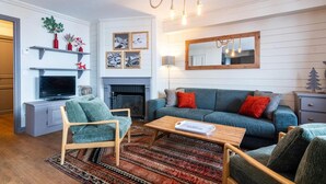Una sala de estar con televisión, sofá, sillas, chimenea y alfombra.